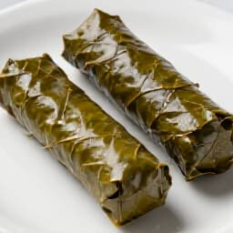 Expertly prepared Armenian and Mediterranean stuffed grape leaves. A platter of meticulously rolled dolma, garnished and ready to serve, representing Beluga