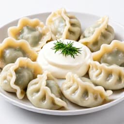 Authentic Russian Pelmeni. A dish of traditional Russian pelmeni dumplings, served with sour cream and dill, showcasing the rich culinary heritage of Beluga Restaurant.