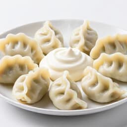 Freshly cooked, steaming Russian pelmeni dumplings served with sour cream