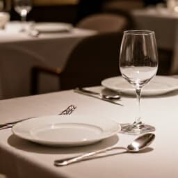 Elegant restaurant dining table set for guests in San Francisco. A beautifully arranged dining table with fine cutlery, glasses, and floral centerpiece, reflecting Beluga